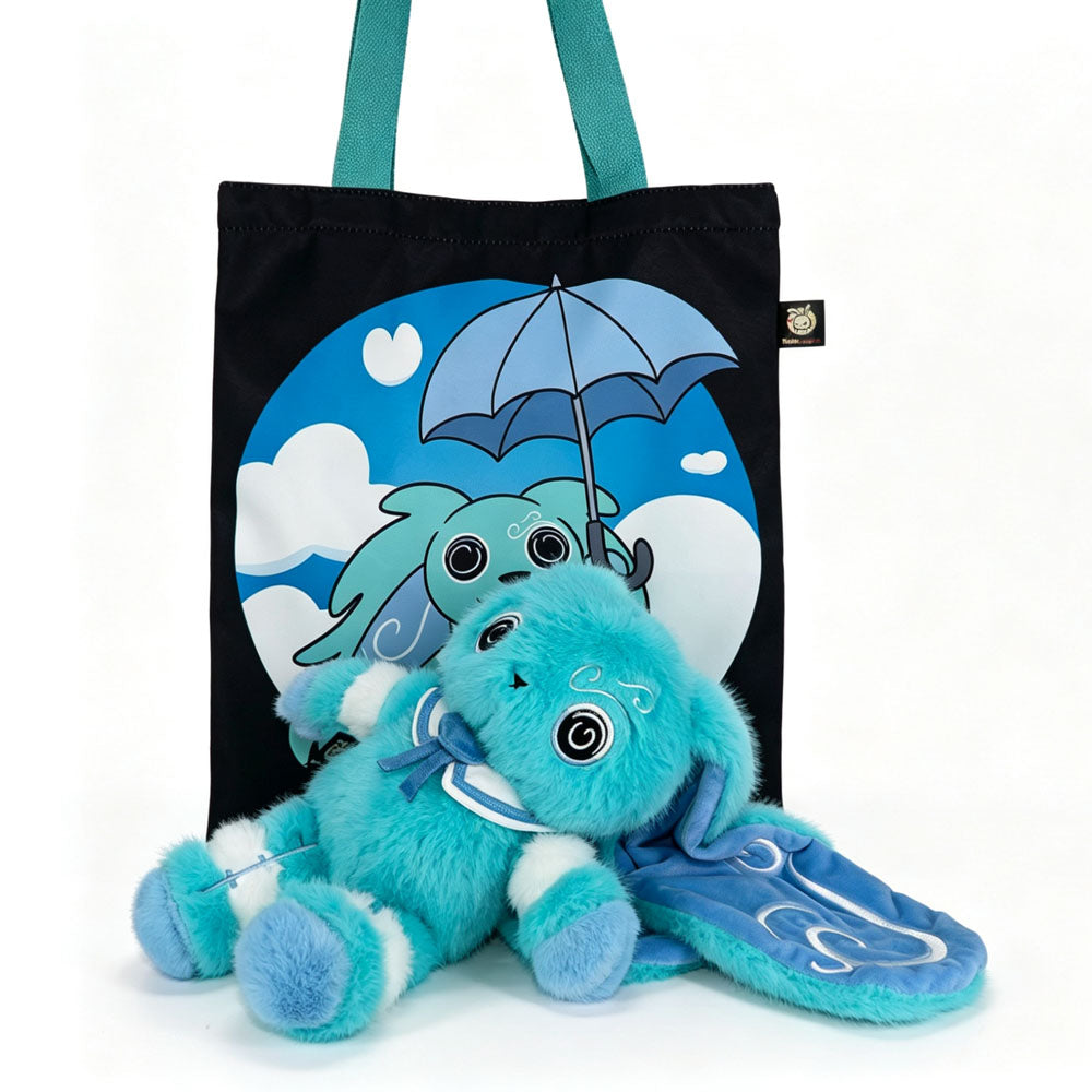 Plush blue Dysautonomia Rabbit toy with floppy ears lies in front of a black tote bag with an umbrella design.