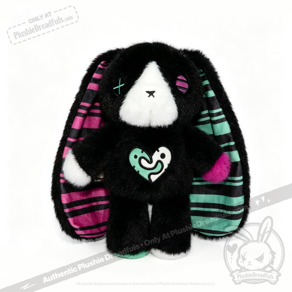 Plush black emotional support bunny with striped ears, colorful patches, and a heart design on its chest, sitting upright.