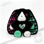 Plush black bunny with striped ears, mismatched eyes—a unique emotional support bunny and thoughtful mental health gift.