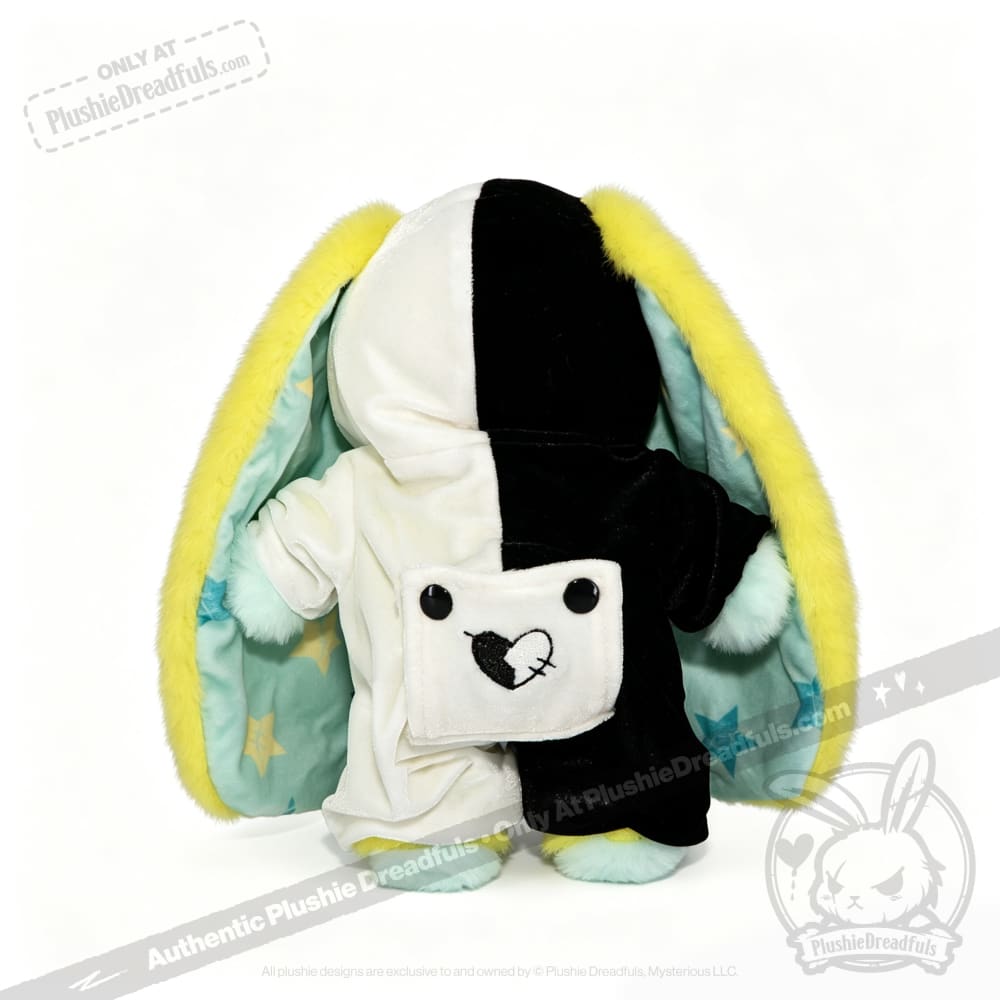 Plushie Dreadfuls bunny toy with split black-and-white fur, yellow-lined ears, and a heart bird pocket design.
