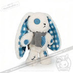 Blueplaid plush bunny toy with blue button eyes, plaid ears, patches, and a gray scarf on a white background.
