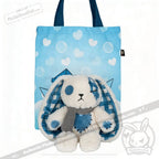 Blueplaid plush bunny with a blue button eye and scarf sits in front of a heart-patterned tote, evoking Seas of Love.
