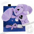 A plush purple bunny with stitched details rests on a LIMITED EDITION blue bag featuring a matching bunny illustration.