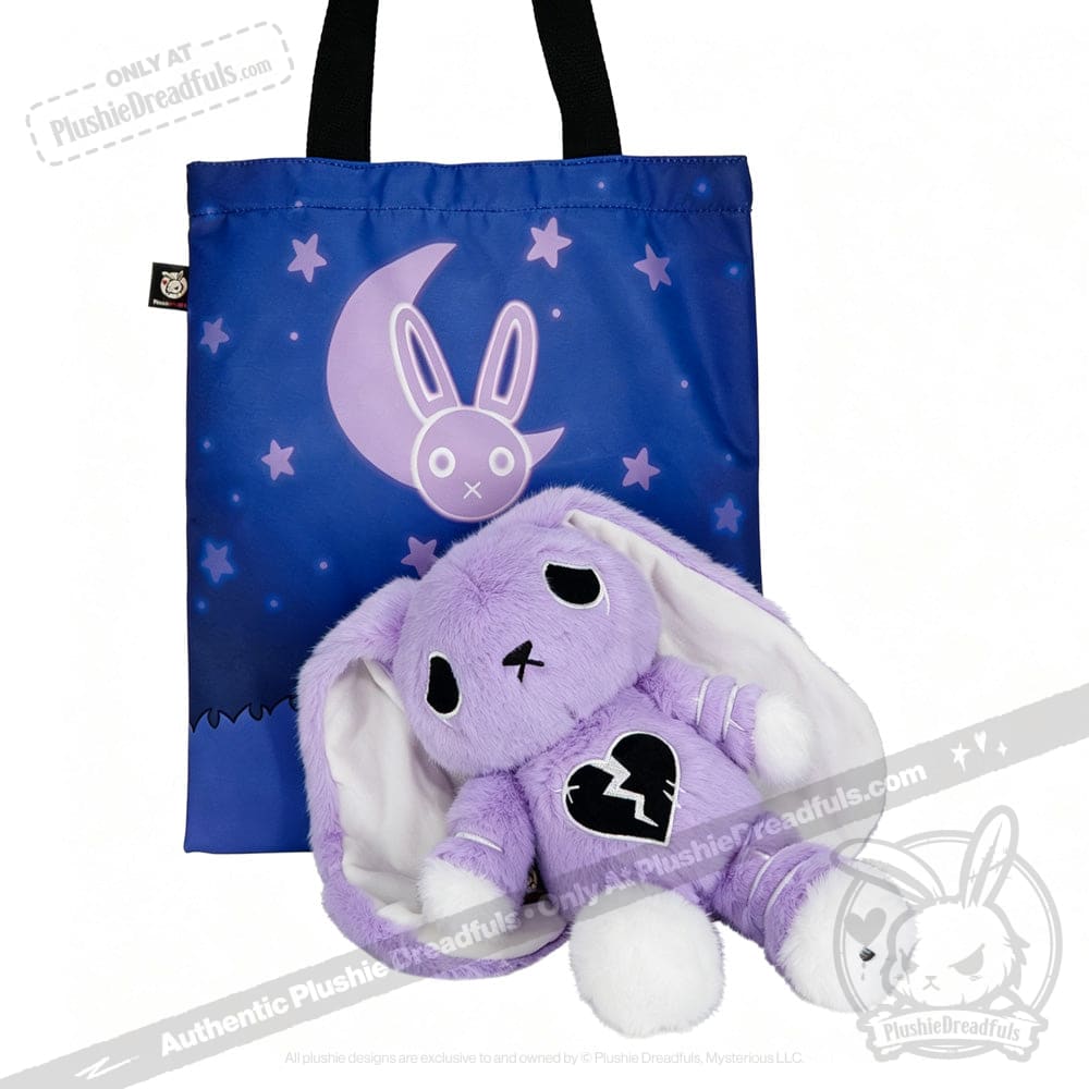 LIMITED EDITION: Purple plush bunny with a broken heart sits before a blue tote bag featuring moon and stars bunny design.