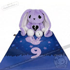 A purple plush bunny for depression awareness with a broken heart sits on a blue mat with stars and number 9.