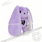 Purple stuffed bunny with floppy ears, black broken heart patch, semicolon symbol, and white stitches—depression awareness.
