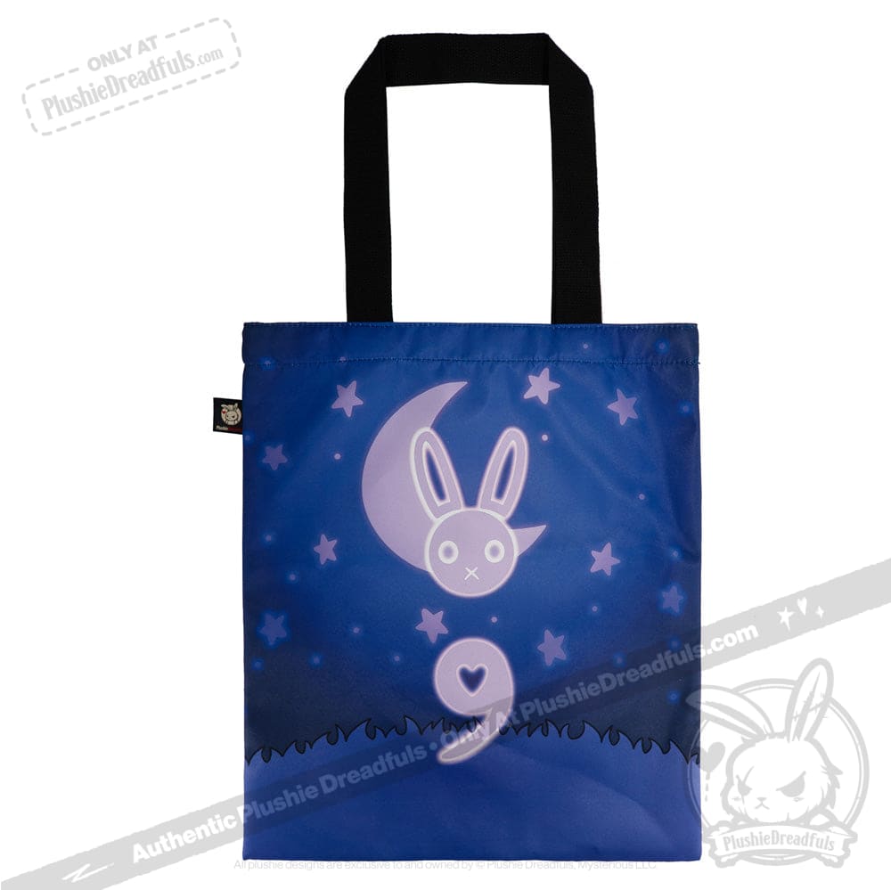 Blue tote bag with glowing bunny-moon, stars, grass, black handles; semicolon symbol for depression awareness.