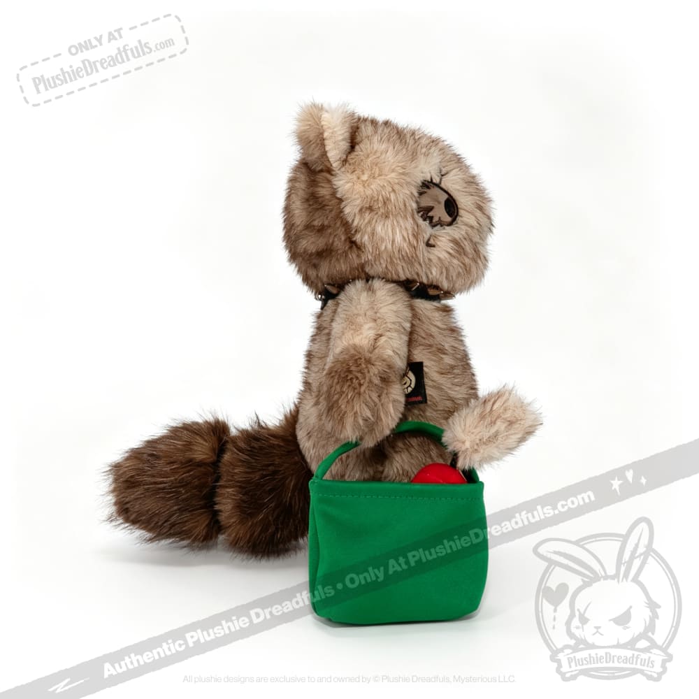 Plushie Dreadfuls raccoon sits upright, holding a green bag with red inside, from plushiedreadfuls.com.