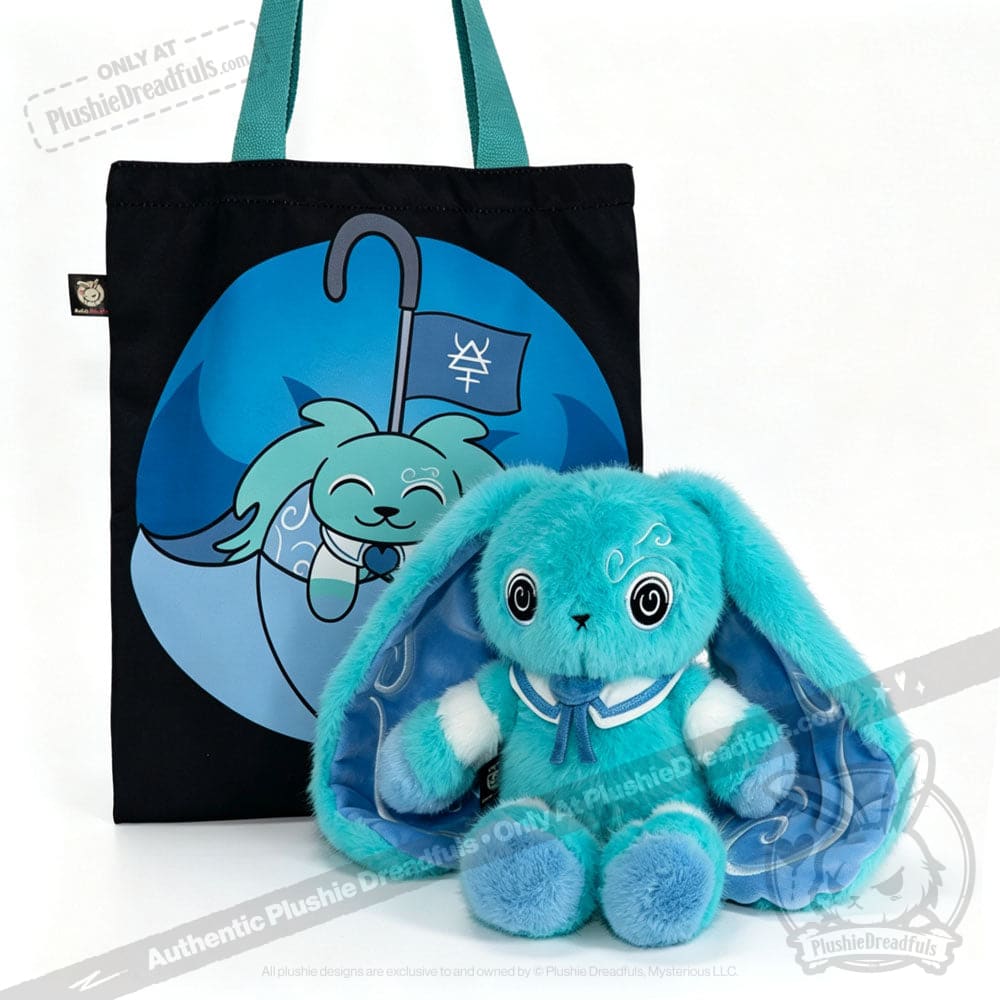 Plush blue bunny, inspired by the Dysautonomia Rabbit, sits before a black tote bag with a blue cartoon animal design.