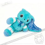 Blue and white Dysautonomia Rabbit plush with a droopy ear, spiral eyes, and a blue ribbon, sitting on its side.