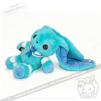 A fluffy blue Dysautonomia Rabbit plush with long ears, white accents, and a blue ribbon, lying on its side.