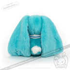 A plush blue Dysautonomia Rabbit sits with its back facing forward, floppy ears down, and white fluffy tail showing.