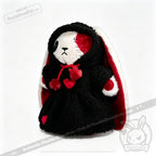 Stuffed bunny in a black Plushie Hoodie with heart details and red accents stands against a white background.