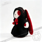 Stuffed bunny in a Plushie Dreadfuls black hooded robe with red and white lining, standing on a white background.