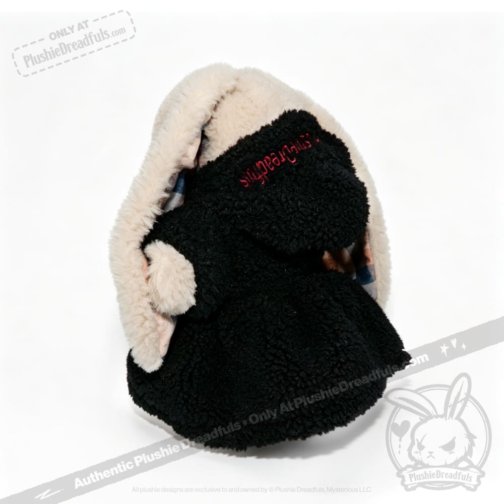 A Plushie Dreadfuls toy in a black and cream plushie hoodie with red embroidery, facing away from the camera.