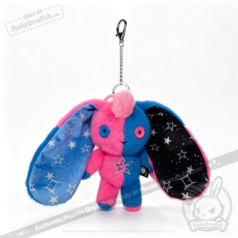 Plushie Dreadfuls Gemini Rabbit keychain with pink-blue fur, big ears, and Gemini star patterns on the inner fabric.
