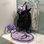 Black backpack, grey vest, and purple bunny plushies with a purple goth floor rug on a white surface.