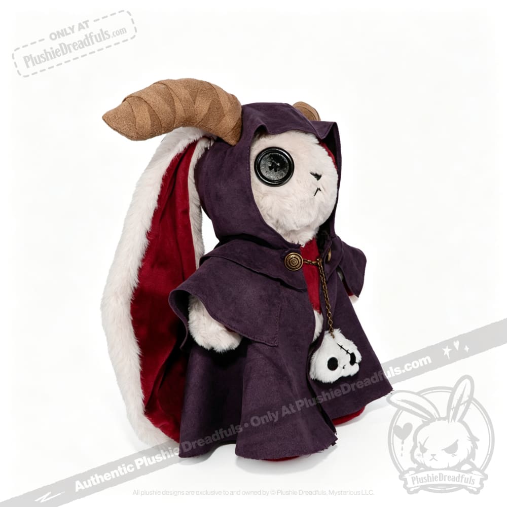 Plushie Dreadfuls toy with a horn, button eye, purple Plushie Cloak, and skull accessory on a white background.