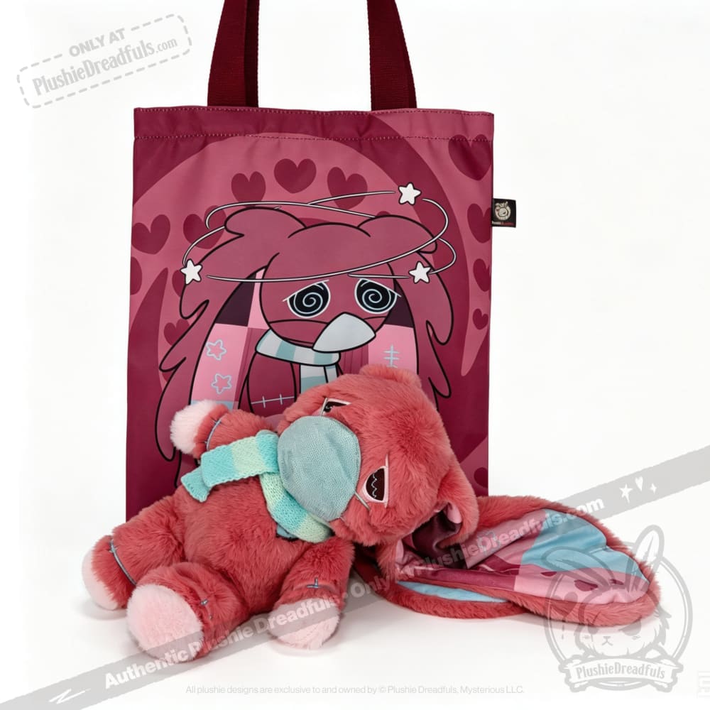 A pink tote bag with a cartoon face, plus an awareness rabbit plushie and matching bunny-eared blanket in front.
