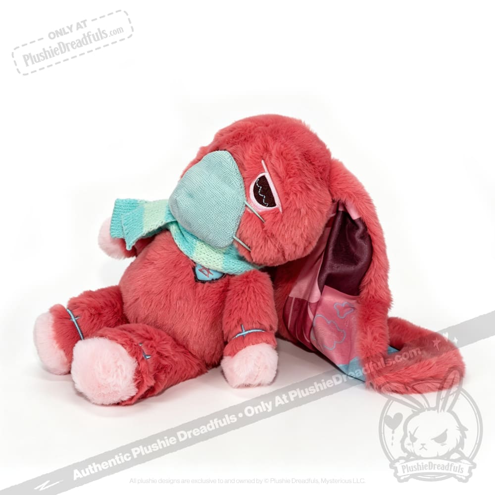 A pink plush bunny with a blue scarf and eye patch sits, making a perfect chronic illness gift or awareness rabbit.