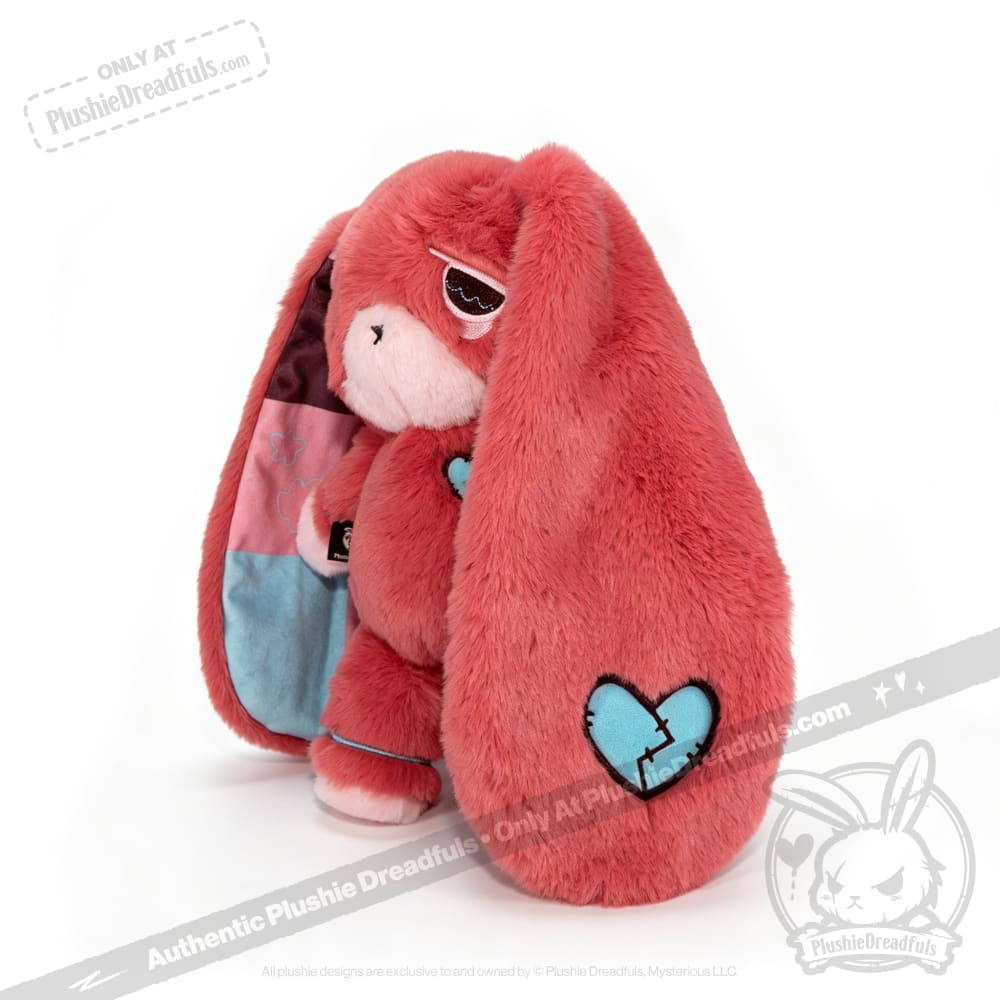Plush pink awareness rabbit with long ears, heart patch, and one patched eye, perfect as a chronic illness gift.