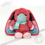 Pink plush bunny with droopy ears and mask, an adorable awareness rabbit, sits in a teal scarf on white background.