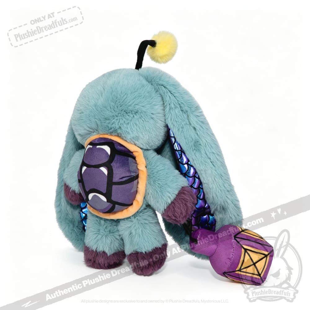 A teal Pisces Rabbit plush with long ears and a purple shell holds a purple and yellow lantern in its soft paws.