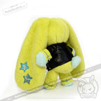 A plush yellow bunny with long ears, blue stars, and a faux leather jacket, facing away from the camera.