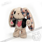 Plush bunny with patchwork, pink heart, plaid ears, and a faux leather plushie jacket stands upright in gray scarf.
