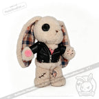Plush bunny with button eyes, plaid-lined ears, faux leather jacket, pink shirt, and stitched patches on its body.