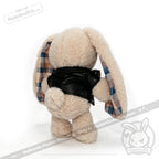 Plush bunny in a black faux leather jacket, showing its back, with plaid inner ears on a white background.