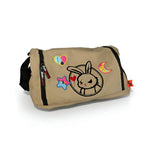 Tan messenger bag with cartoon bunny, plushie clothes, night sky iron on patches, side zipper, and black shoulder strap.