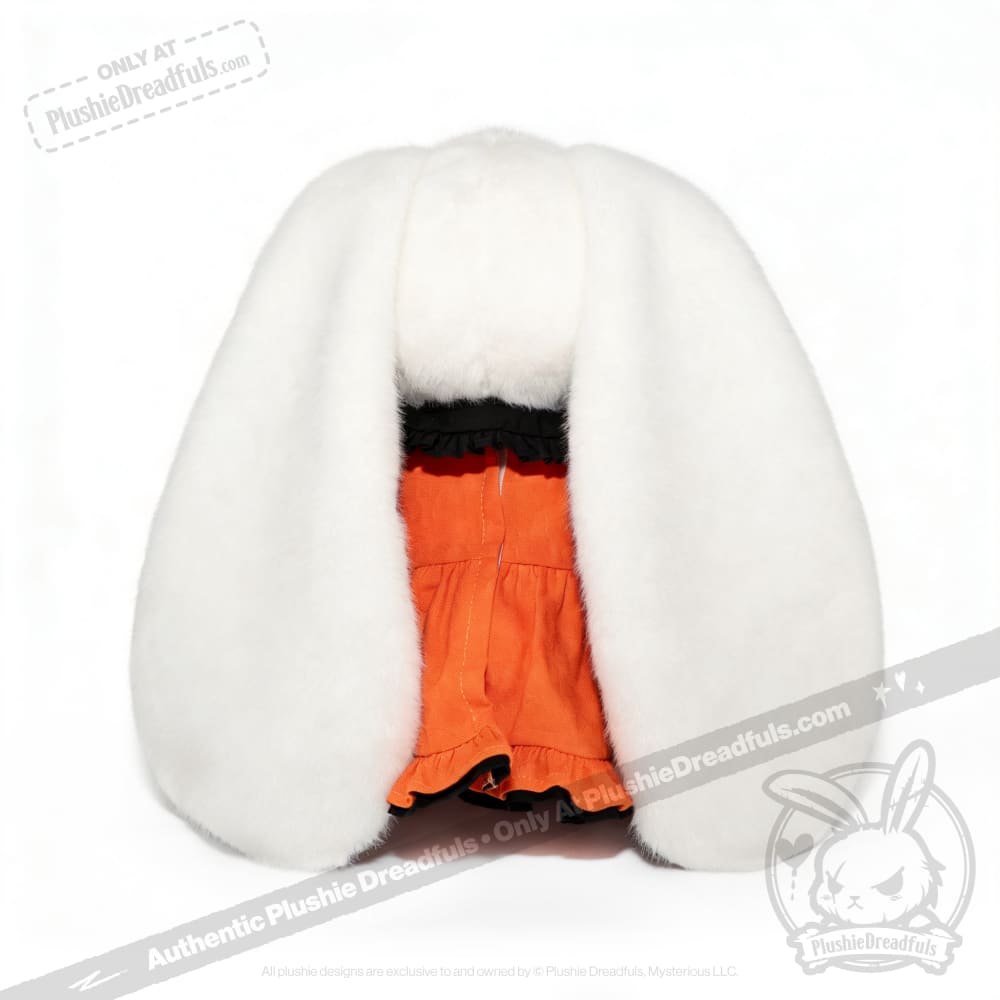 A Wonderland plush toy hat, shaped like bunny ears, tops an orange ruffled outfit against a white background.