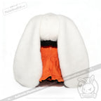 A Wonderland plush toy hat, shaped like bunny ears, tops an orange ruffled outfit against a white background.