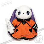 Plush white bunny in orange dress, a sweet Wonderland plush toy, holding a small bunny, purple-lined ears peeking out.