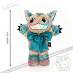 Victorian McGee's Autism Acceptance Cheshire Cat - Plush Stuffed Animal features multicolor fur, a large rainbow grin, a big blue bow, pointy ears, and claws. Shown against a white background with a vertical measurement indicating its height of 31.5 cm (12.4 inches), this whimsical plush toy is inspired by Alice in Wonderland and designed to celebrate autism acceptance.