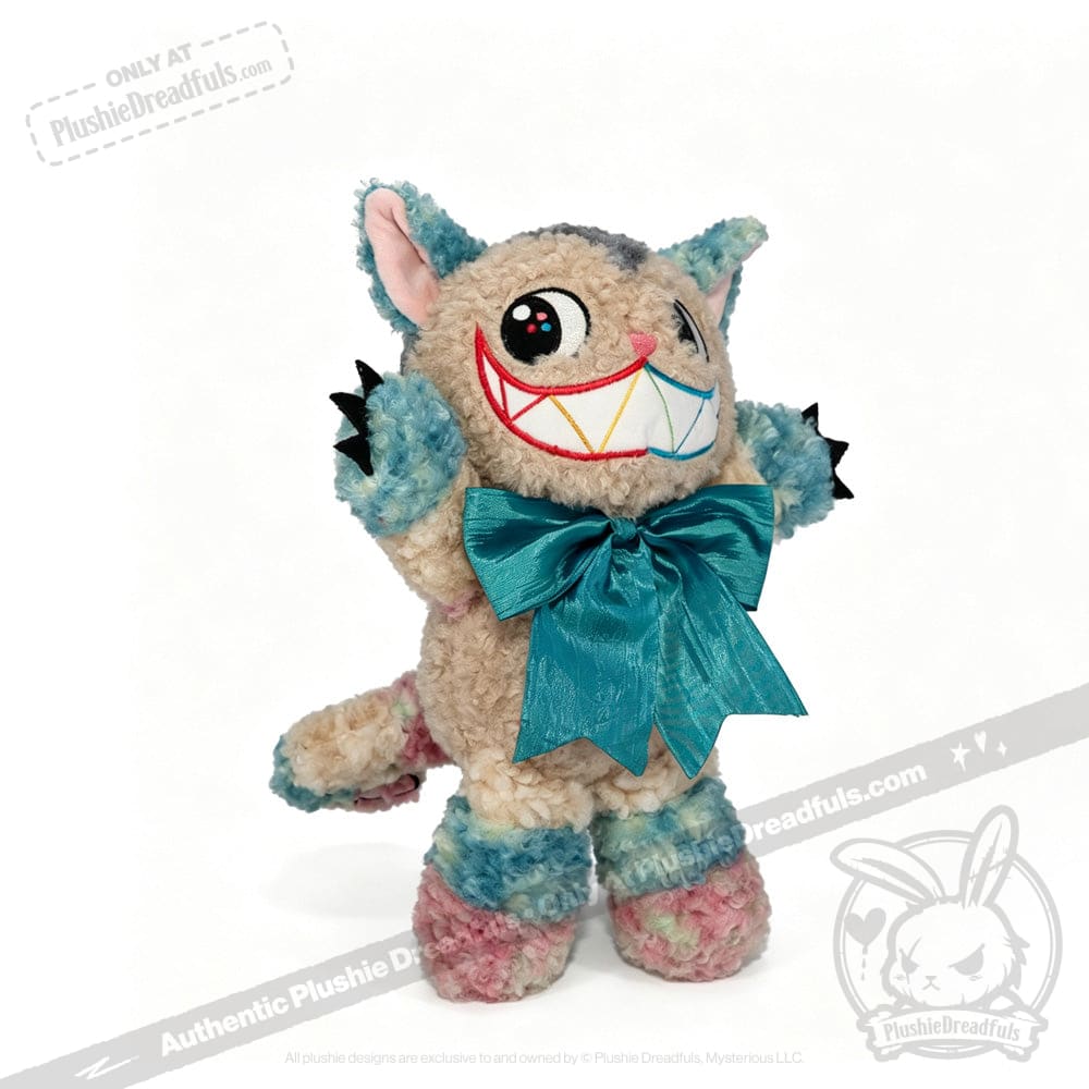 Victorian McGee's Autism Acceptance Cheshire Cat - Plush Stuffed Animal features a cheerful upright cat with cartoonish eyes, pointy ears, and soft blue, pink, and beige fur. Adorned with a large turquoise bow around its neck, this whimsical plush toy is inspired by Alice in Wonderland and brings inclusive charm to any collection.