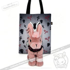 A pink plush bunny sits in front of a gray tote from plushiedreadfuls.com, a limited edition plushie release.